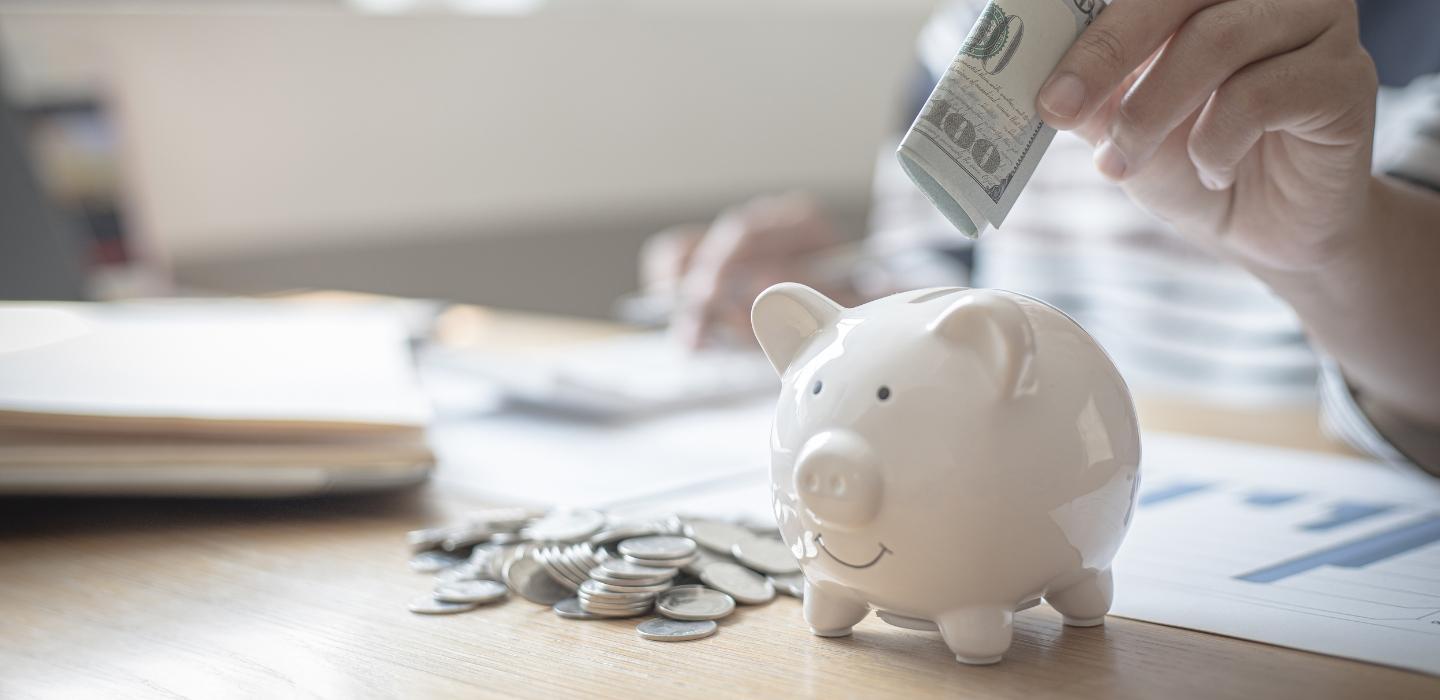 Tirelire cochon avec une personne qui met de l'argent dedans